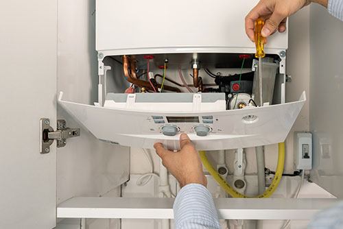 Heating technician repairing a residential boiler in Paramount