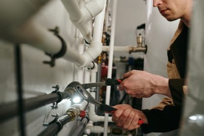 Technician inspecting commercial plumbing pipes in Paramount
