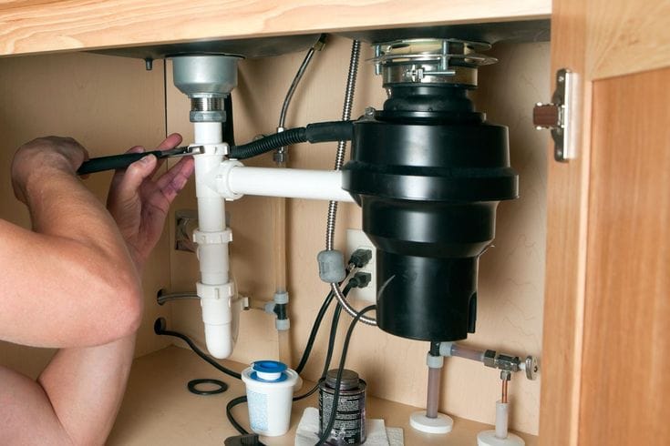 Plumber repairing a garbage disposal in Paramount