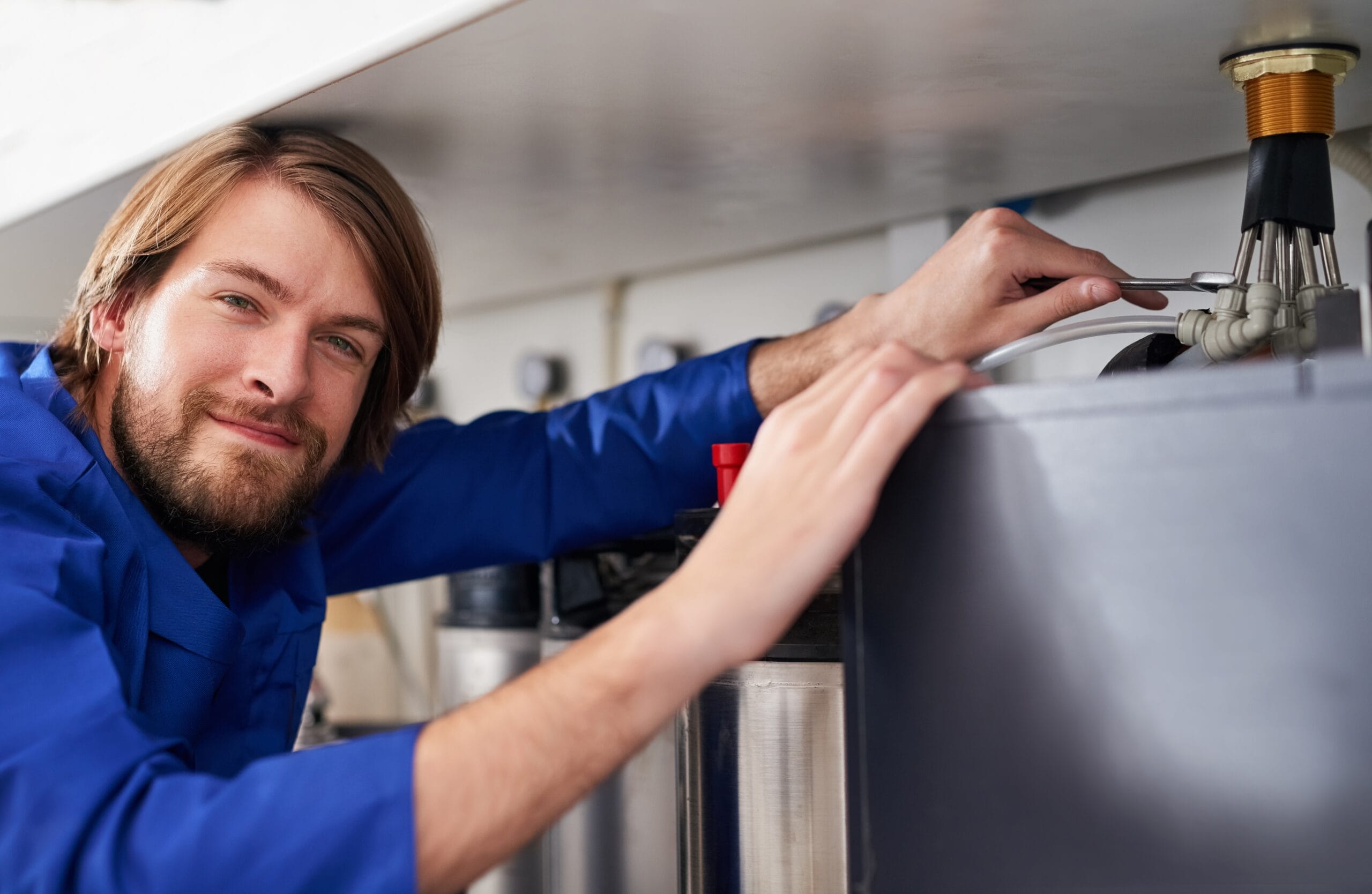 Technician servicing a residential water heater tank in Paramount